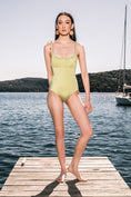 Load image into Gallery viewer, Model wearing Ruched Bust Shoestring One Piece Swimsuit in Green Leaf in an editorial shoot on a jetty with water in the background